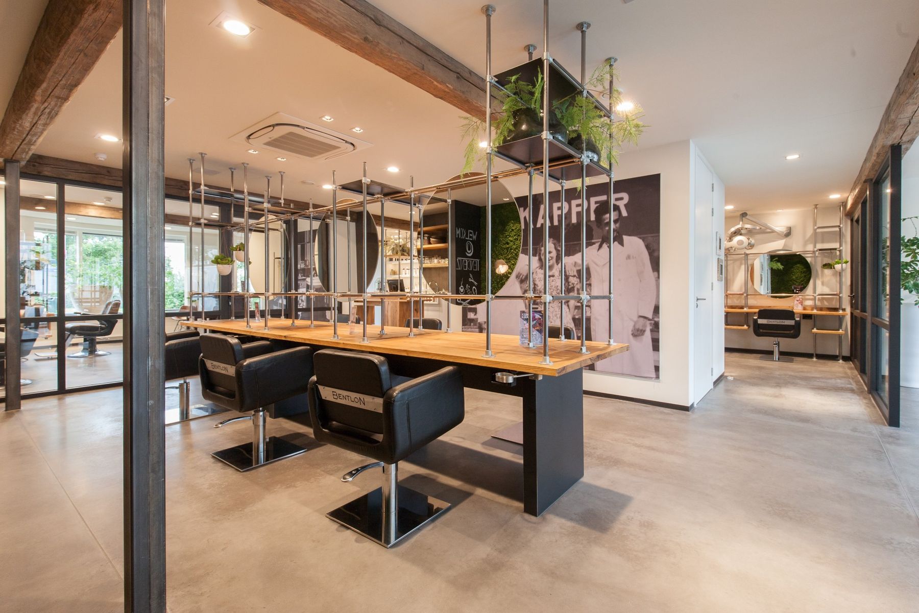 Salon met een grote zwart-witfoto van kappers uit vroeger tijd aan de wand